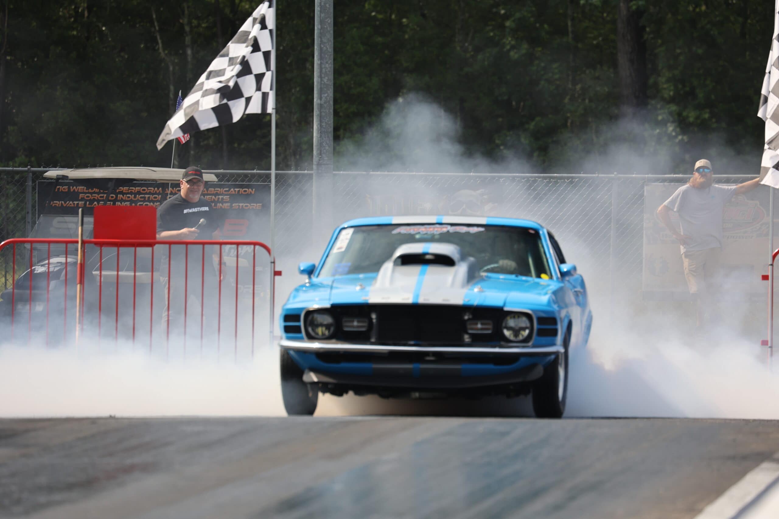 Blue classic muscle car performing burnout at Mustang Week event.