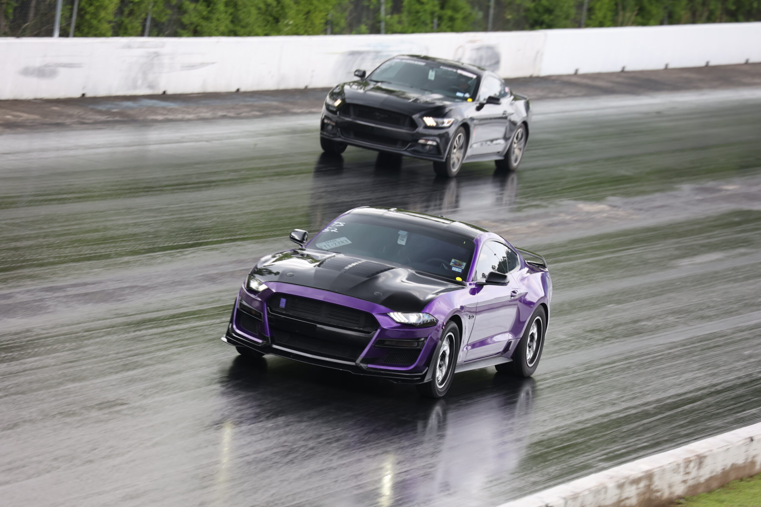 Two Ford Mustangs racing on a wet drag strip at Mustang Week.