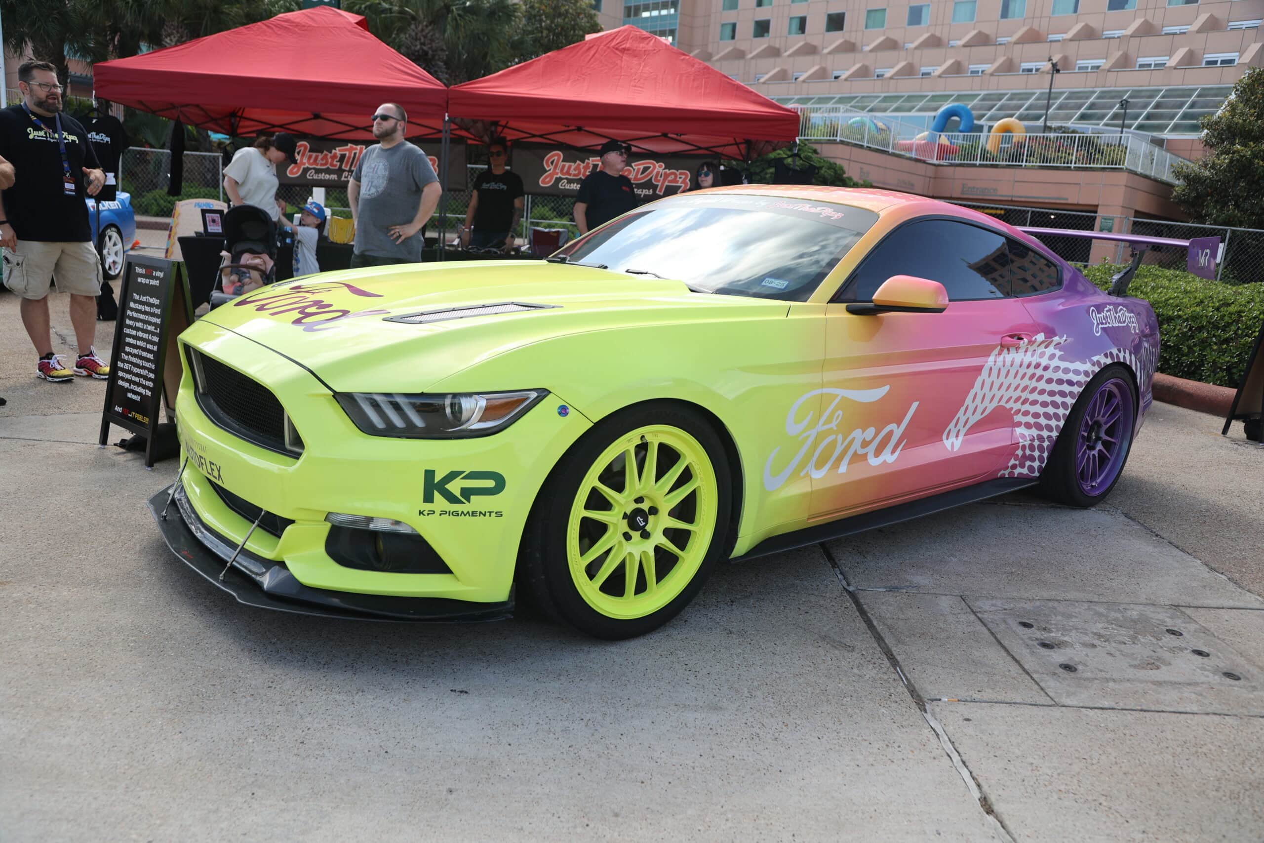 Bright yellow and pink Ford Mustang race car at Mustang Week event.