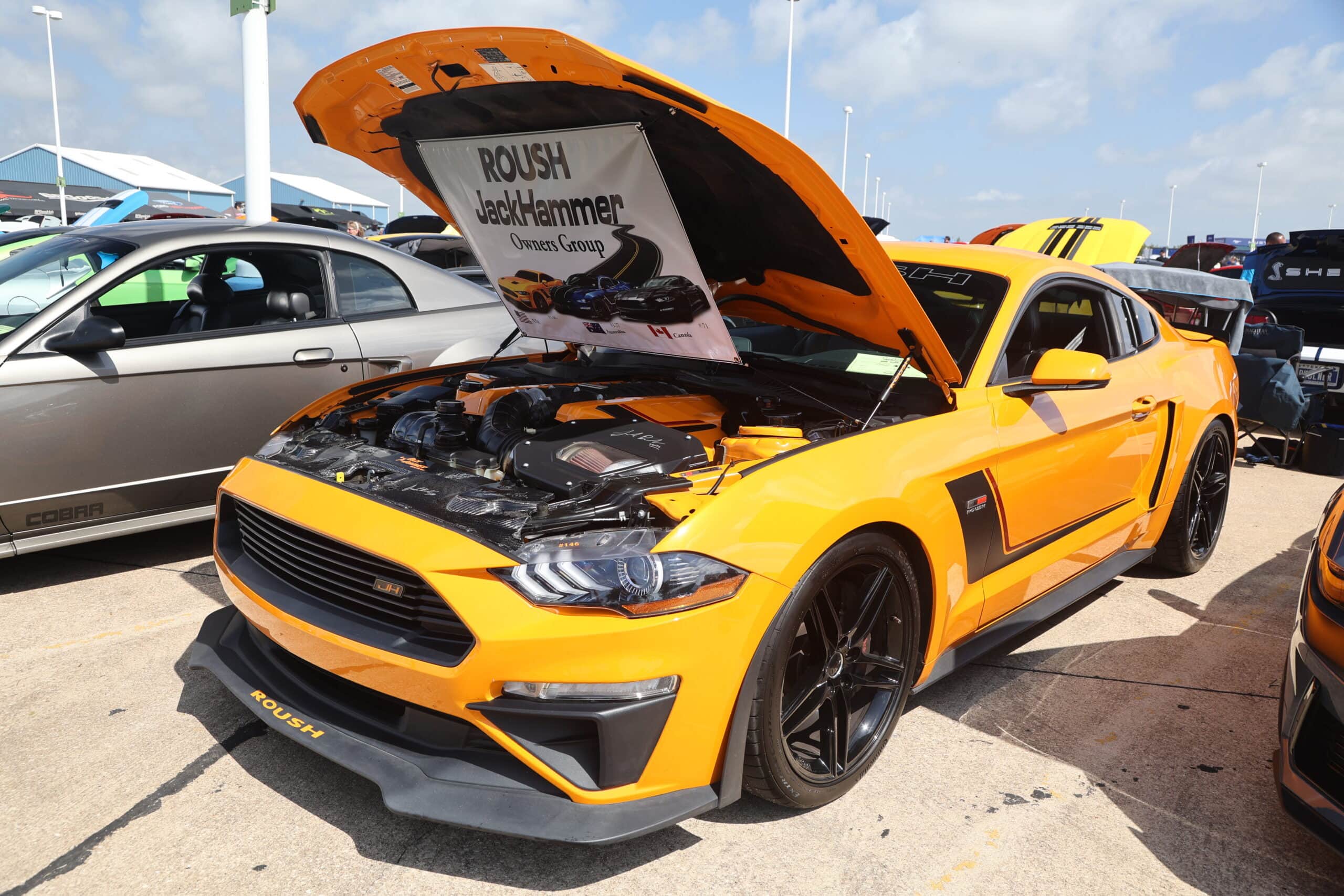 Yellow Ford Mustang with open hood at Mustang Week event.