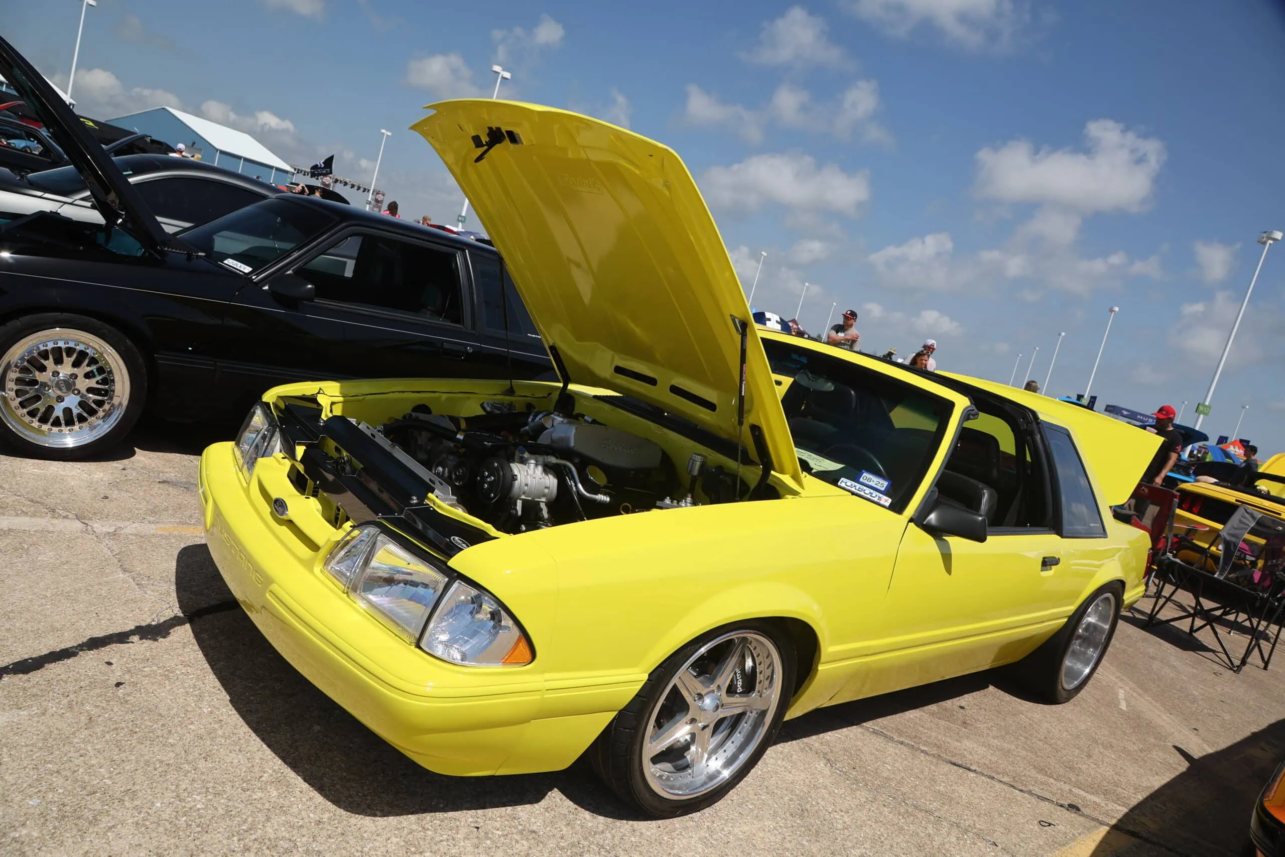 Yellow Ford Mustang with open hood at Mustang Week car show.