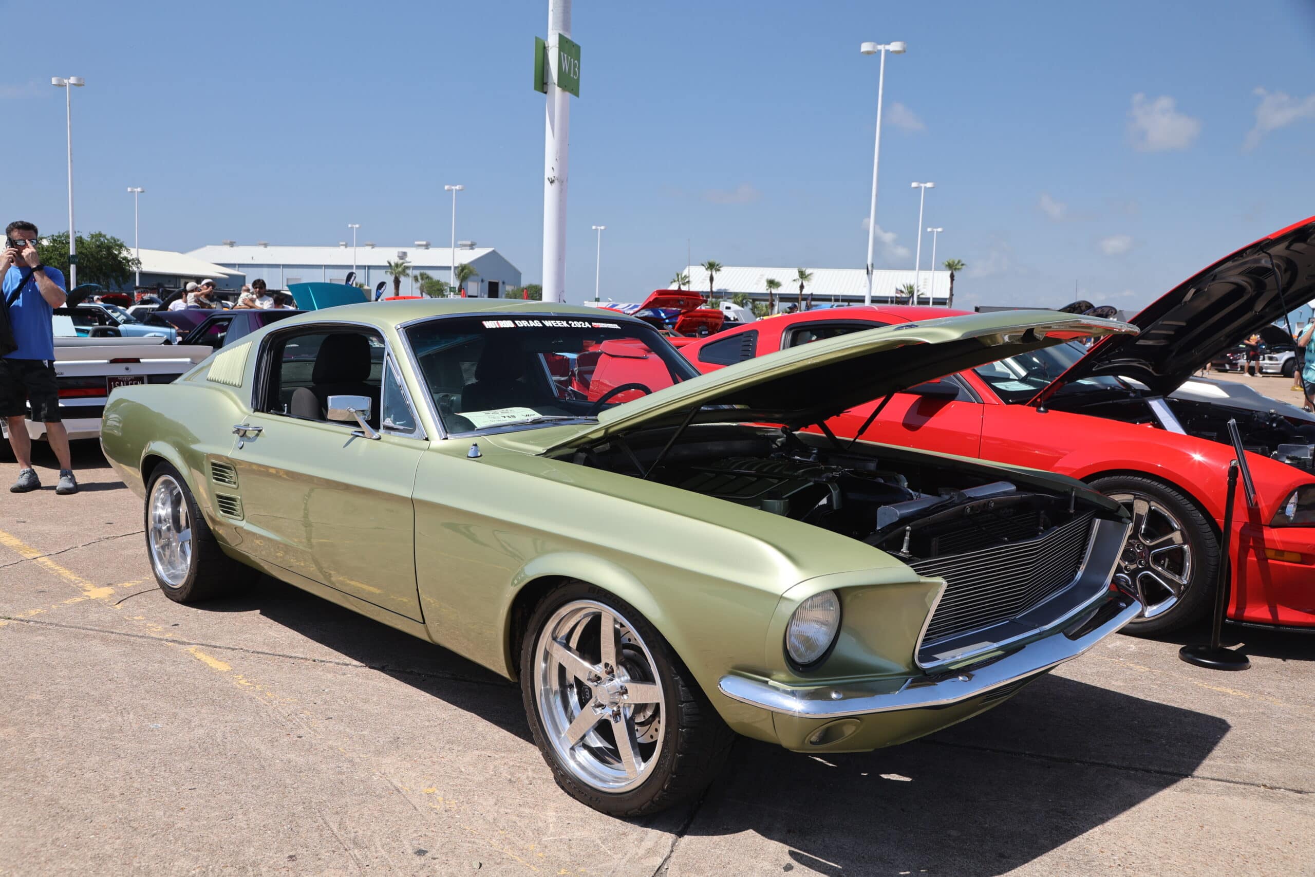 Vintage green Ford Mustang with open hood at Mustang Week event.