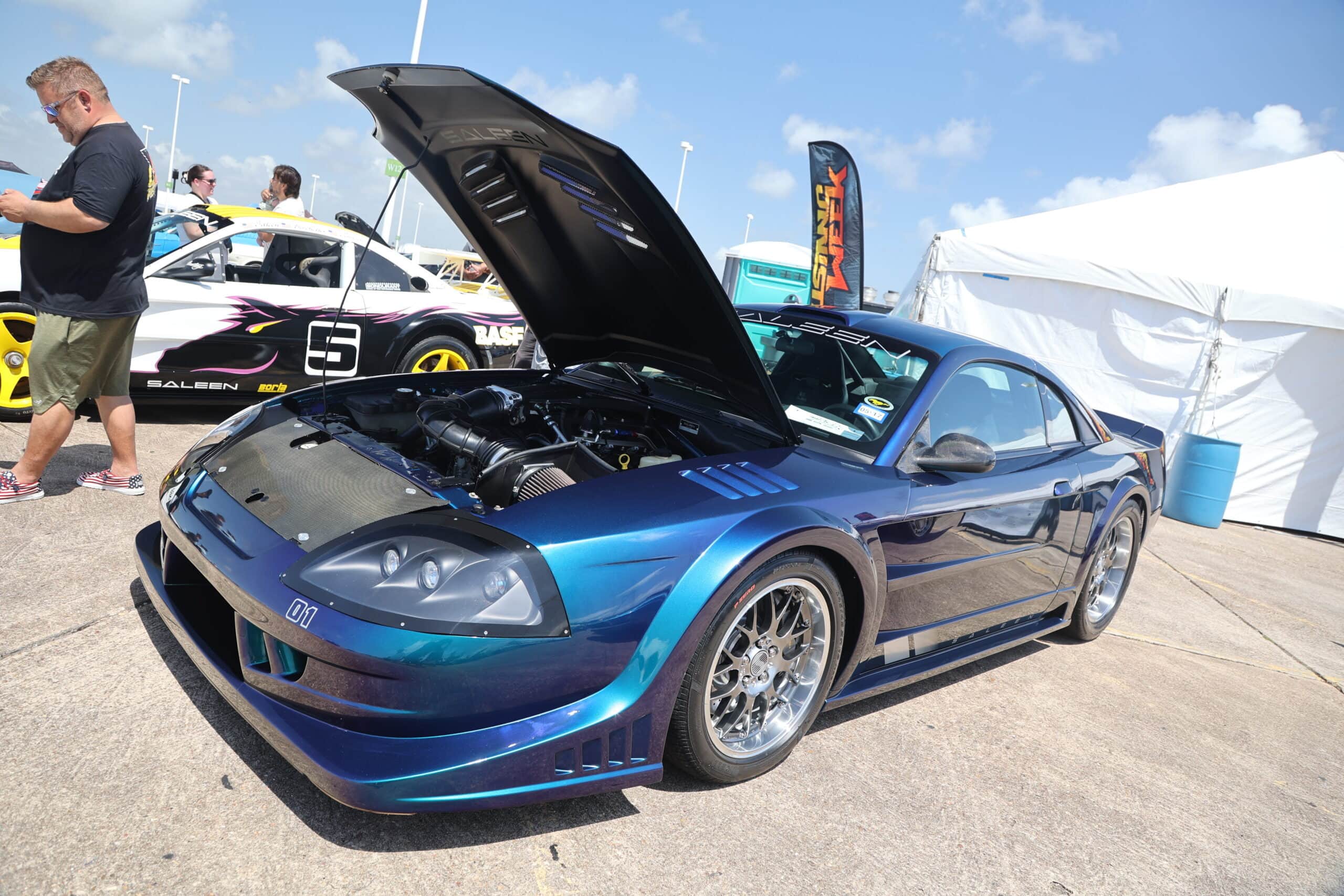 Blue Ford Mustang with open hood at Mustang Week event.