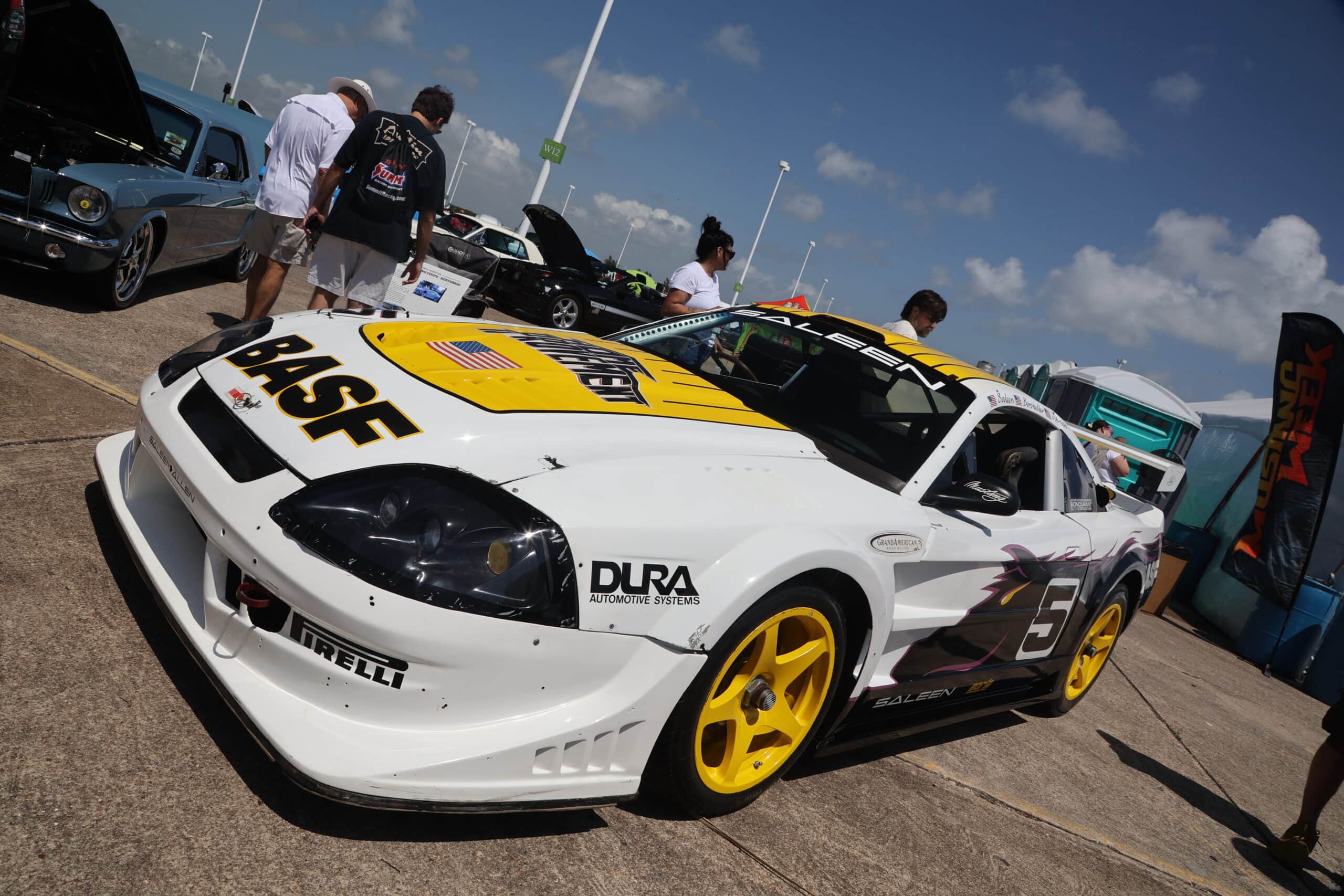 White race car with yellow wheels at Mustang Week event in Texas 2025.