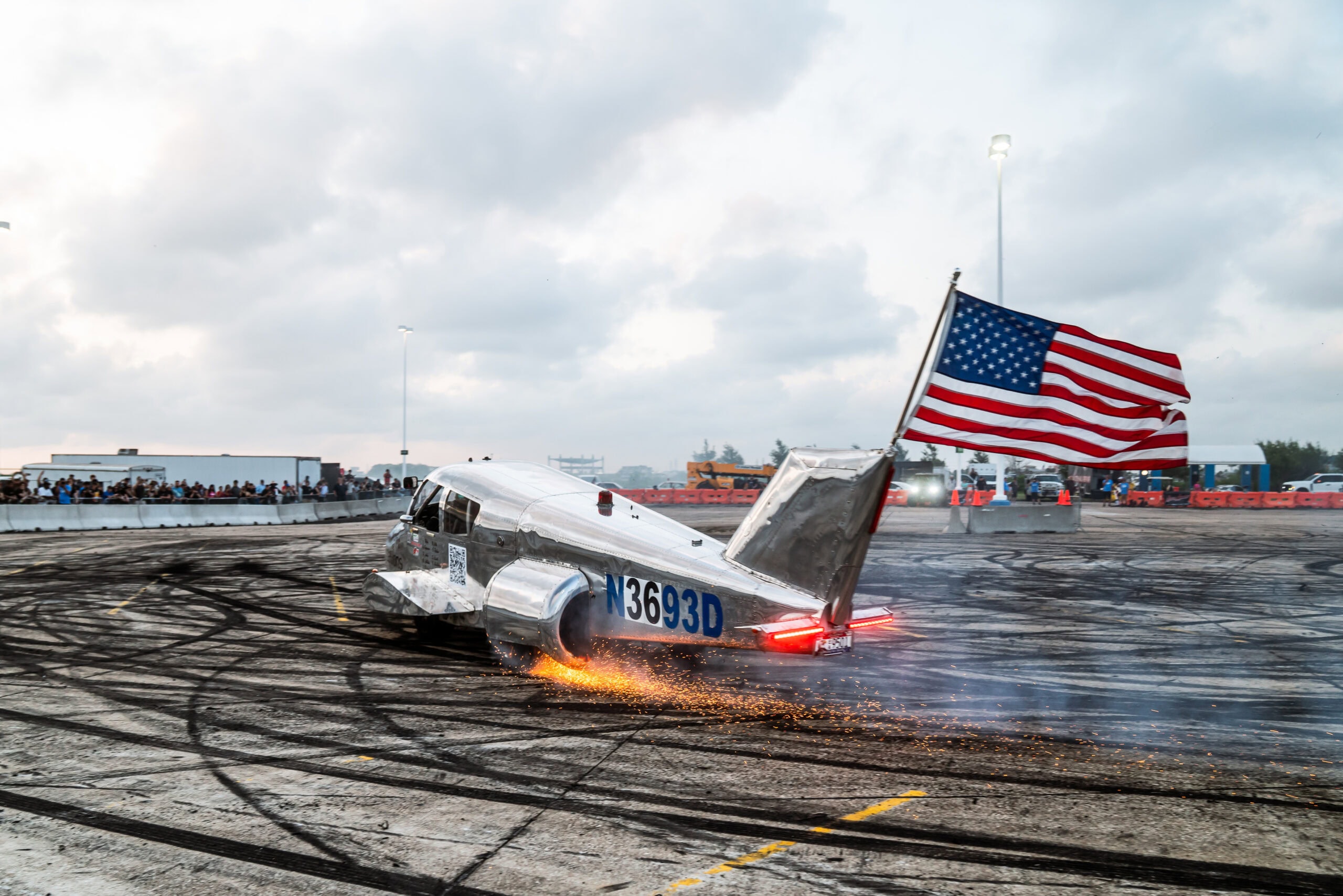 Car performing a stunt with American flag at Mustang Week event.