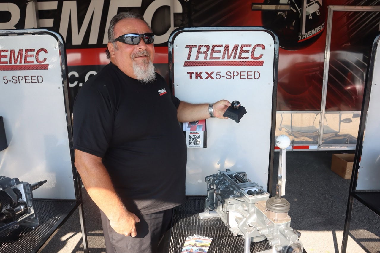 Man at Mustang Week event with engine display and TREMEC signage.