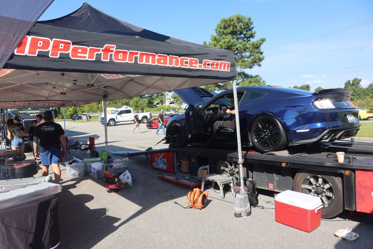 High-performance blue Mustang on a race trailer at Mustang Week event.