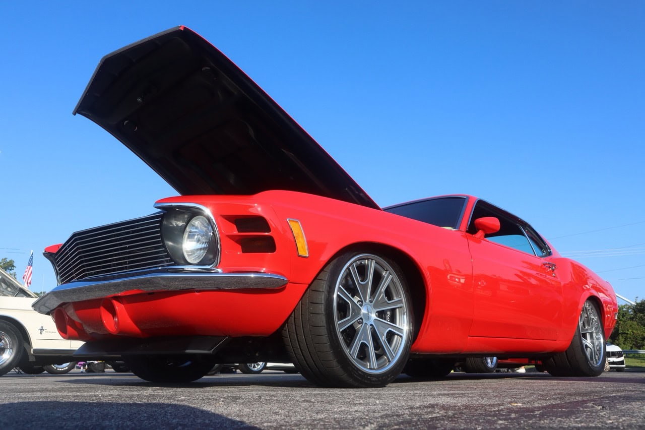 Classic red Ford Mustang with open hood at Mustang Week event.