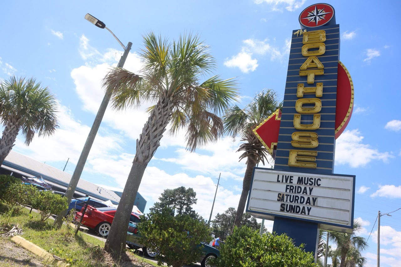 Iconic sign for Mustang Week event in Myrtle Beach with palm trees and clear sky.