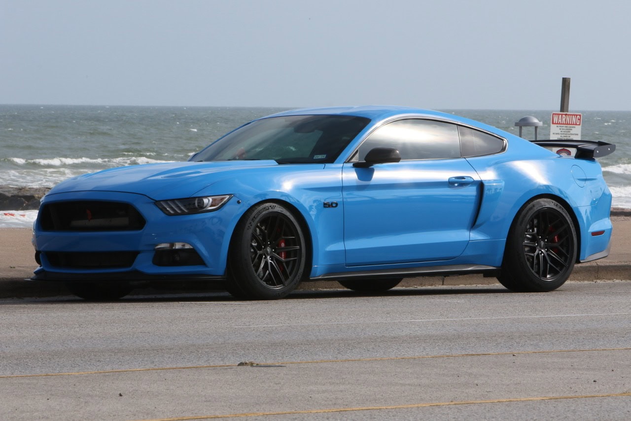 Blue Ford Mustang sports car parked by the beach during Mustang Week event.
