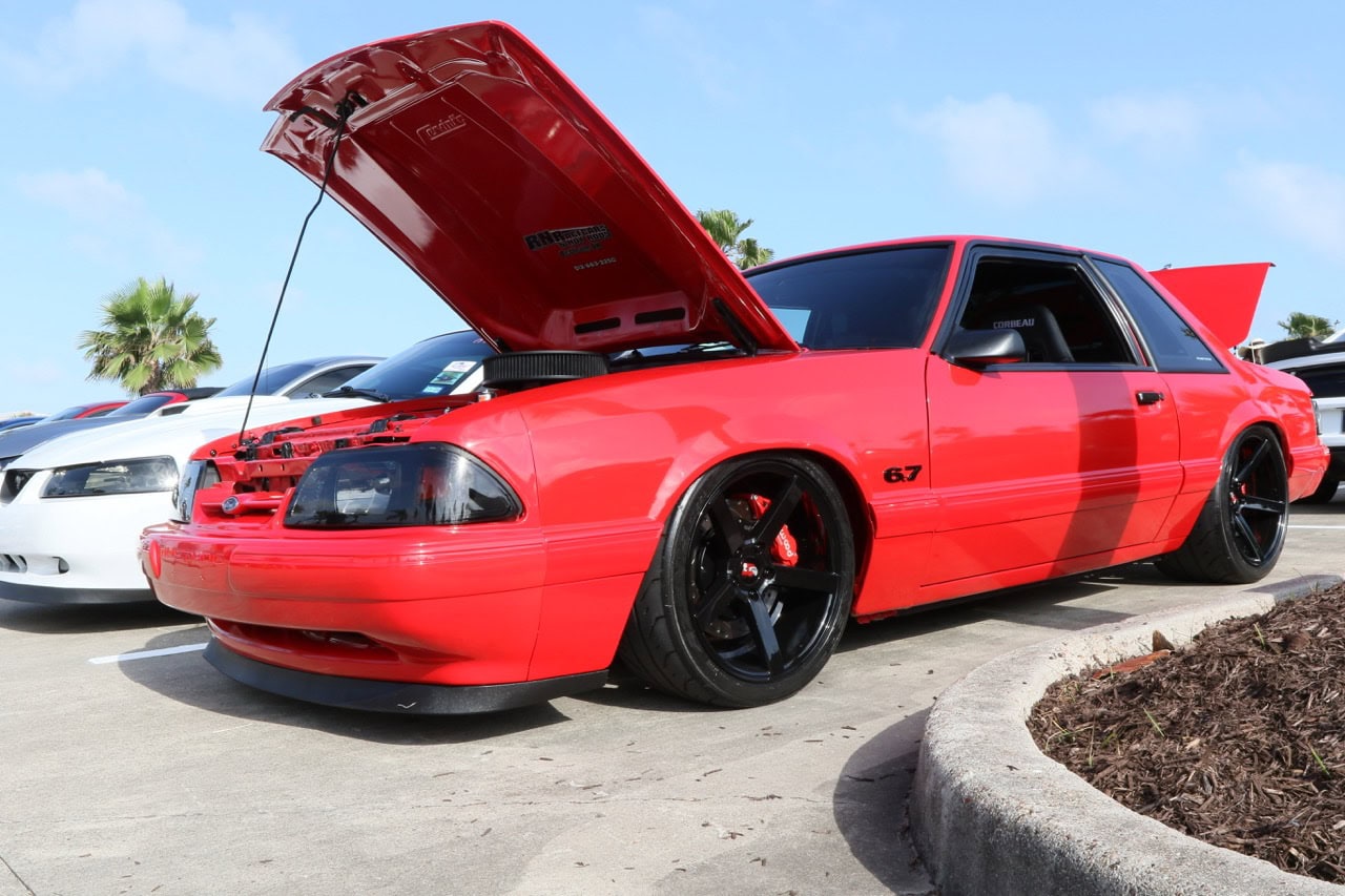 Classic red Ford Mustang with open hood at Mustang Week event.