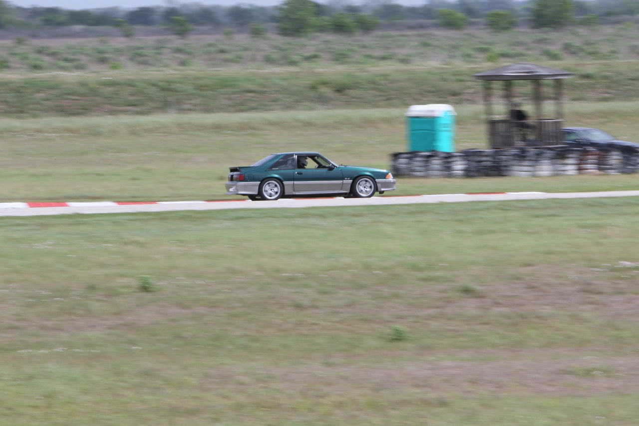 Classic Ford Mustang racing on a track at Mustang Week event.