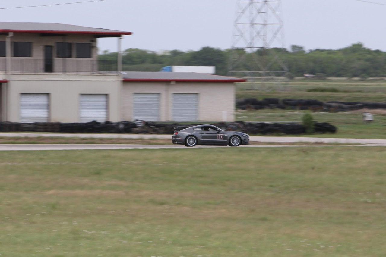 Classic Ford Mustang racing at Mustang Week event.