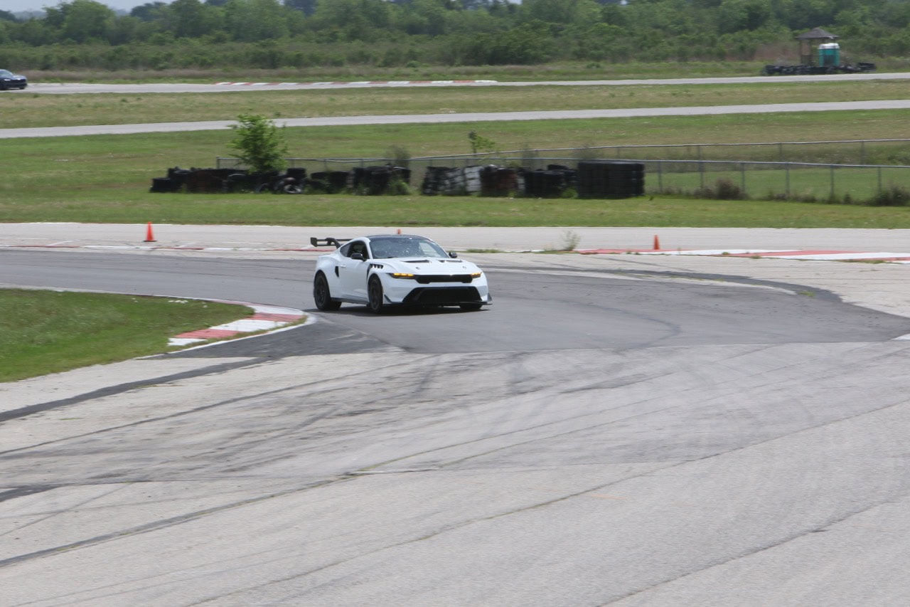 White Ford Mustang racing car on track at Mustang Week event.
