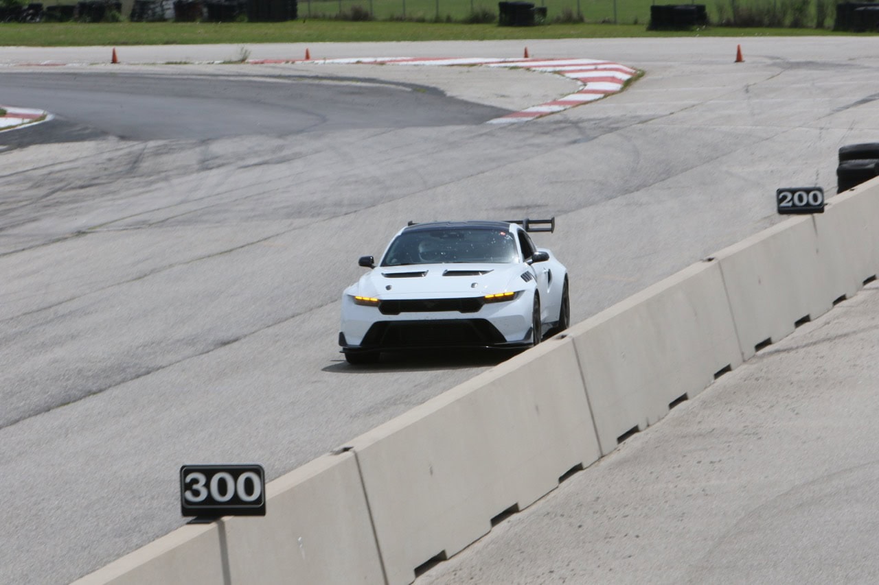 Mustang Week race car navigating a track with safety barriers.