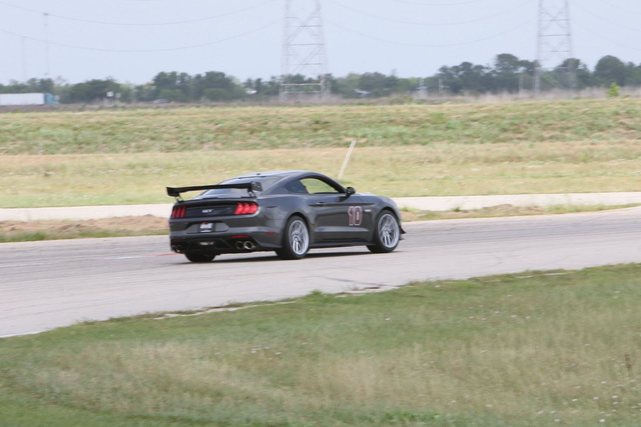High-speed Mustang racing on the track during Mustang Week event.