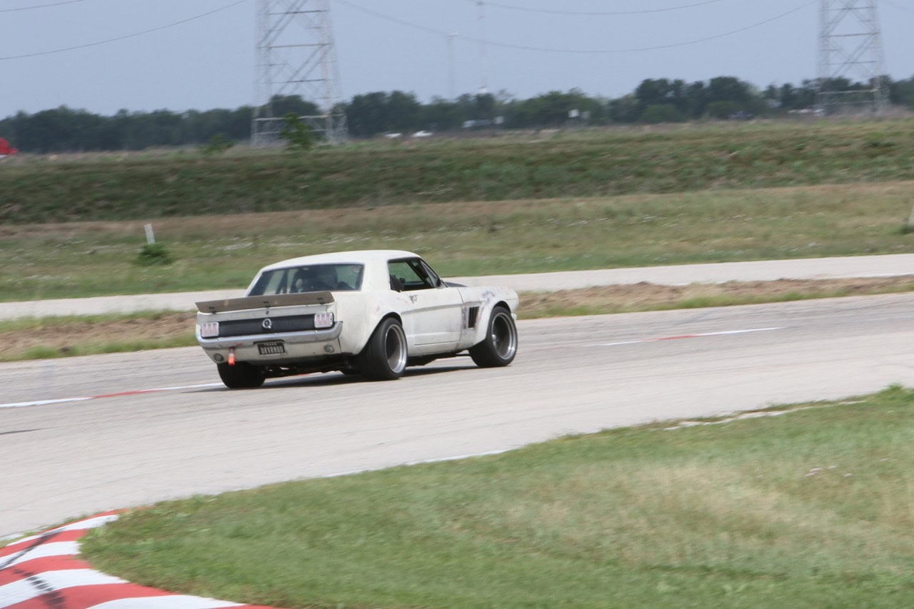 Classic Ford Mustang racing at Mustang Week event.