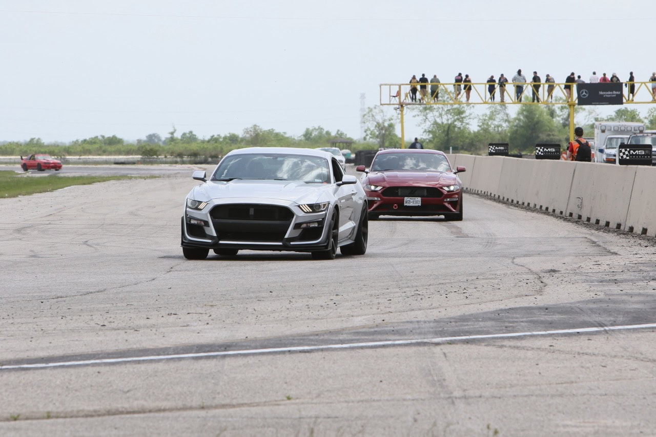 High-performance Ford Mustangs racing on the track at Mustang Week event.