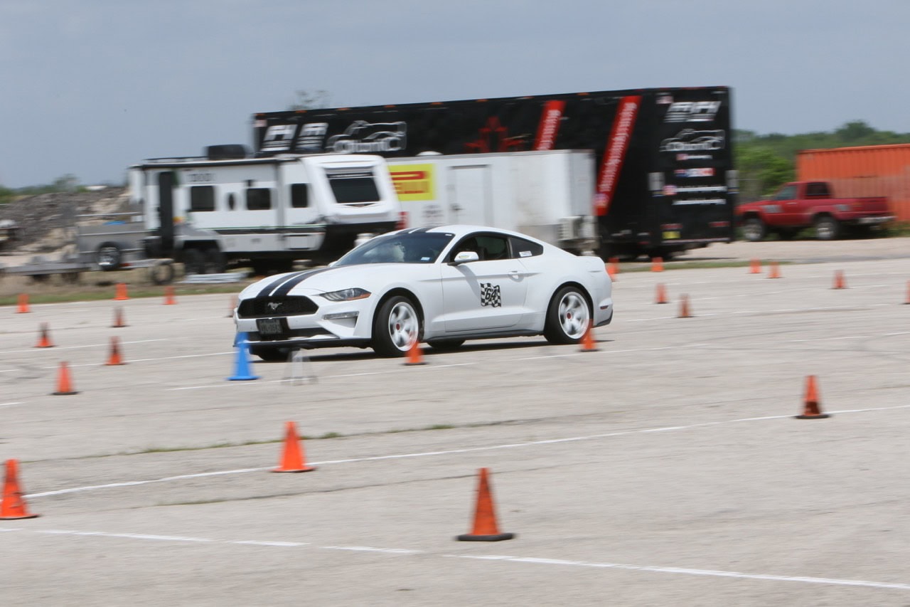 White Ford Mustang navigating a driving course with cones at Mustang Week.