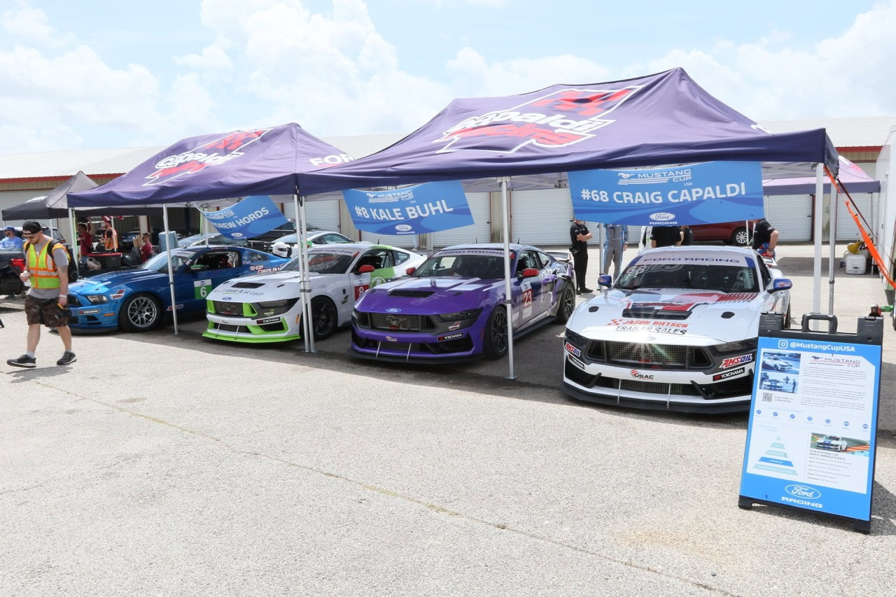 Mustang Week car display with racing cars under tents at Texas 2026.