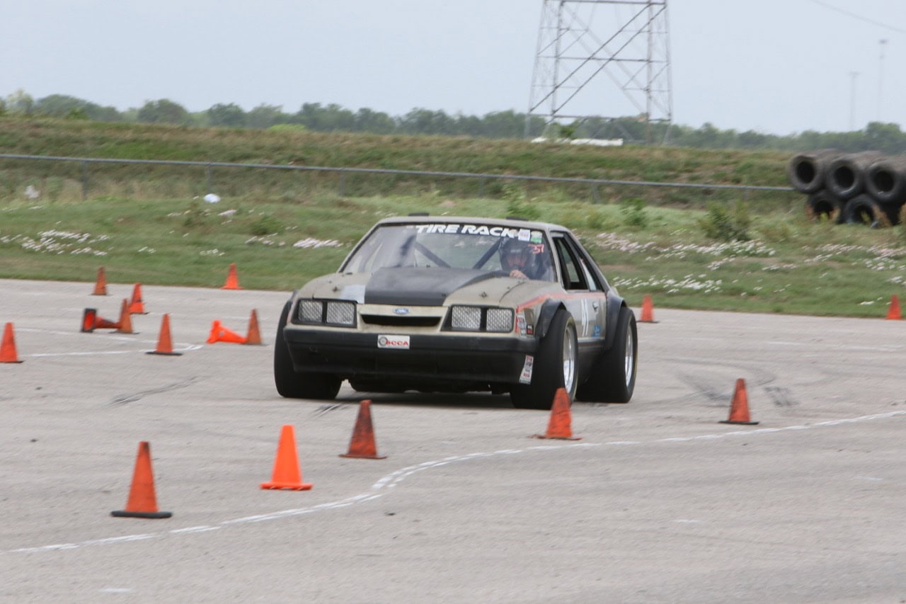 Classic Ford Mustang navigating a slalom course at Mustang Week event.