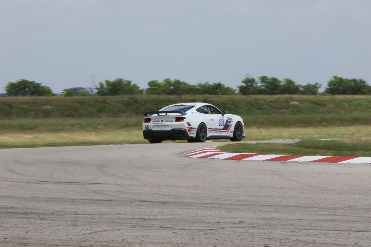High-speed Mustang race car on track at Mustang Week event.