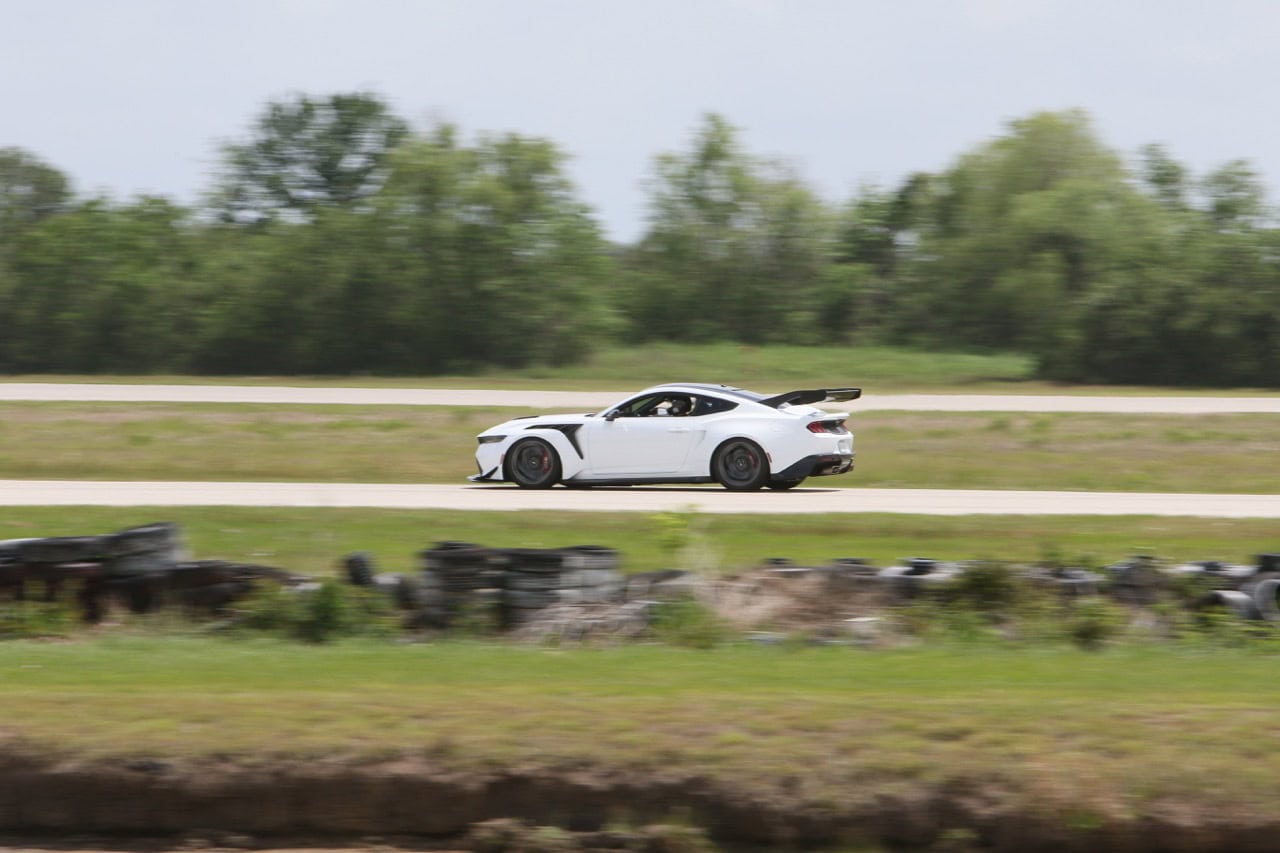 High-speed white Mustang racing on open road in Texas.
