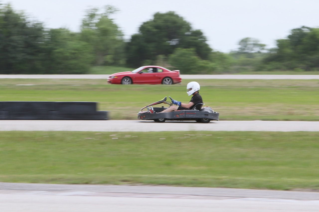 Classic and modern Ford Mustangs racing on a track at Mustang Week Texas 2026.