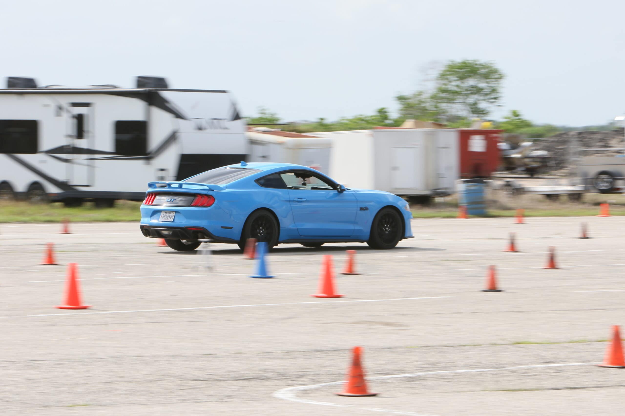 Blue Ford Mustang performing a driving maneuver at Mustang Week event.