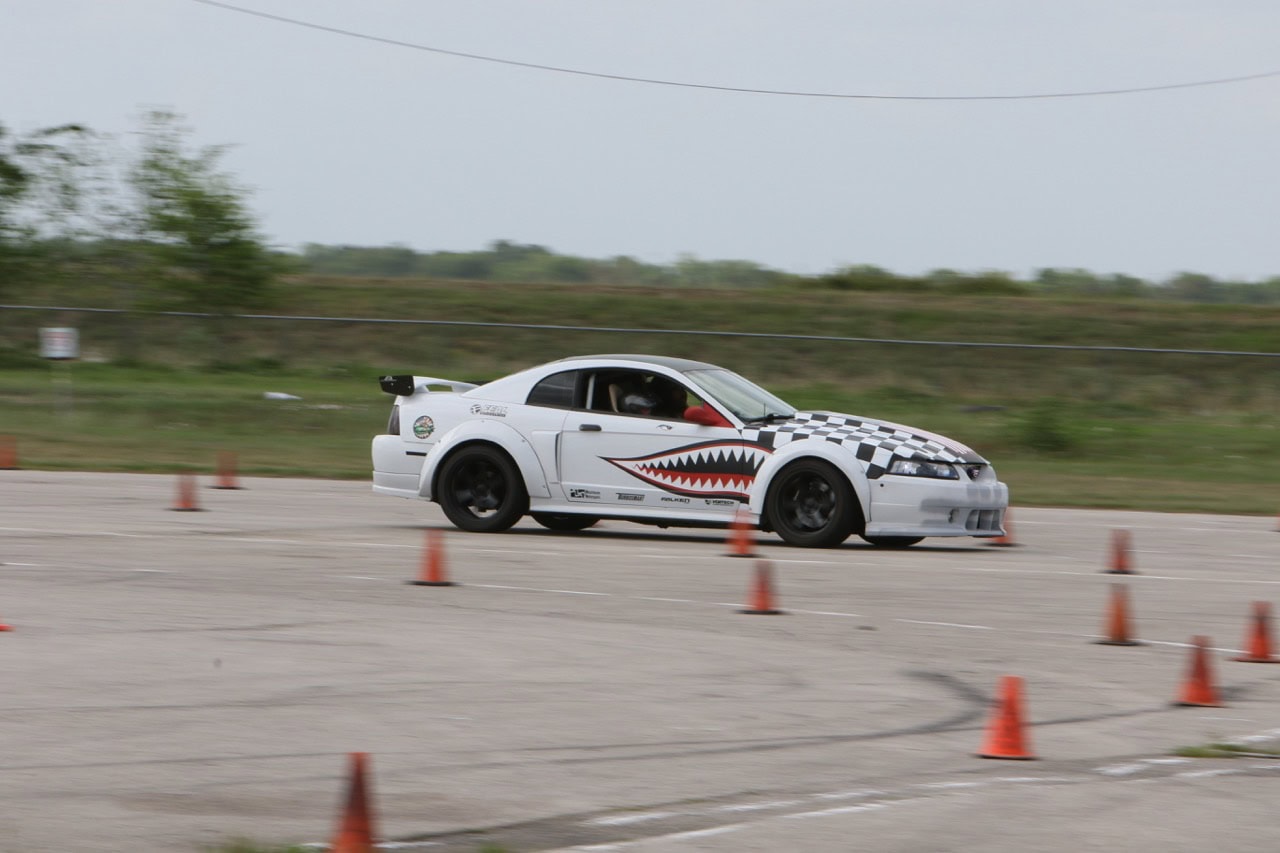 White sports car with shark mouth design navigating cones at Mustang Week.