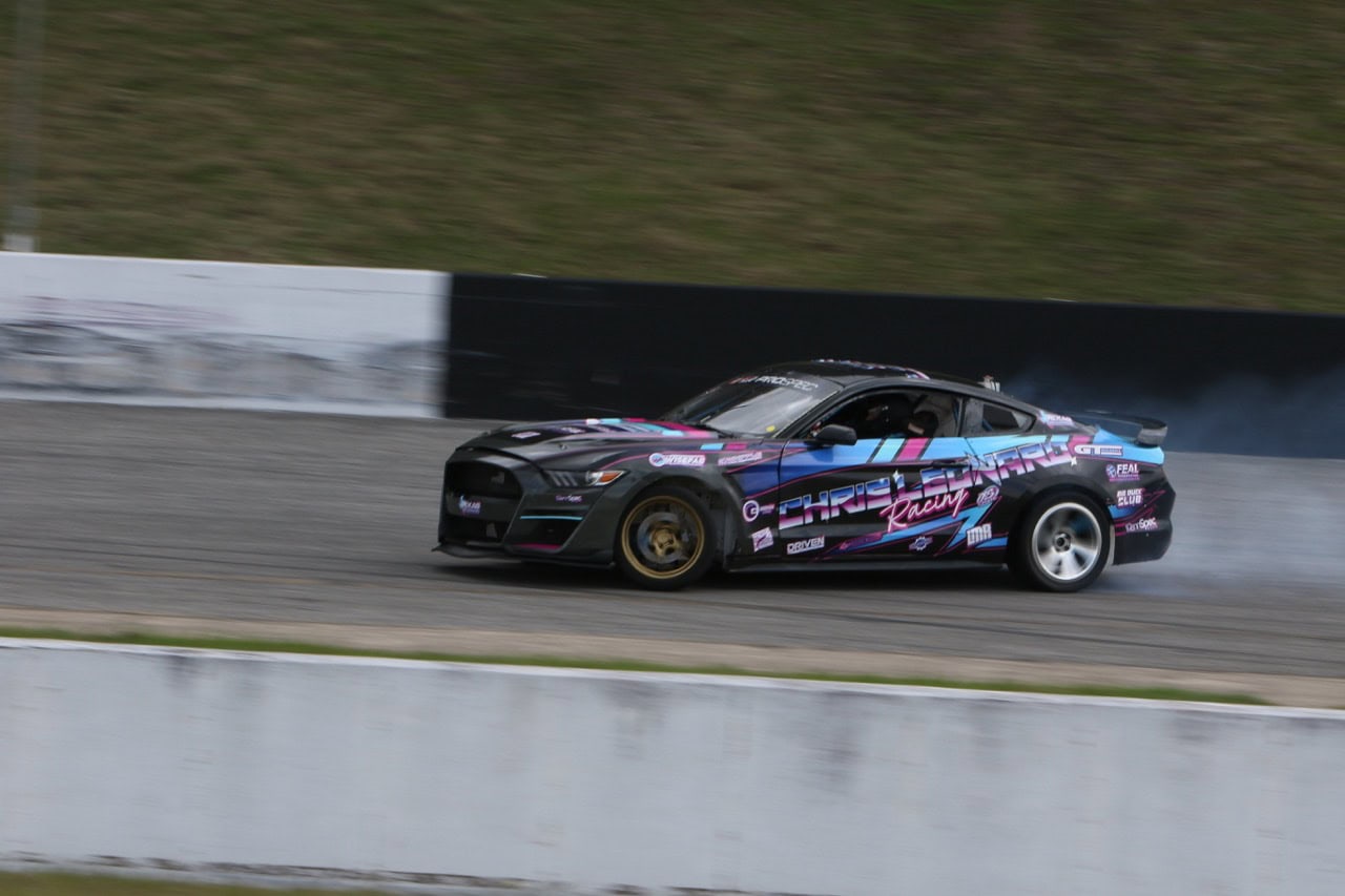 High-performance Mustang drifting on race track during Mustang Week event.