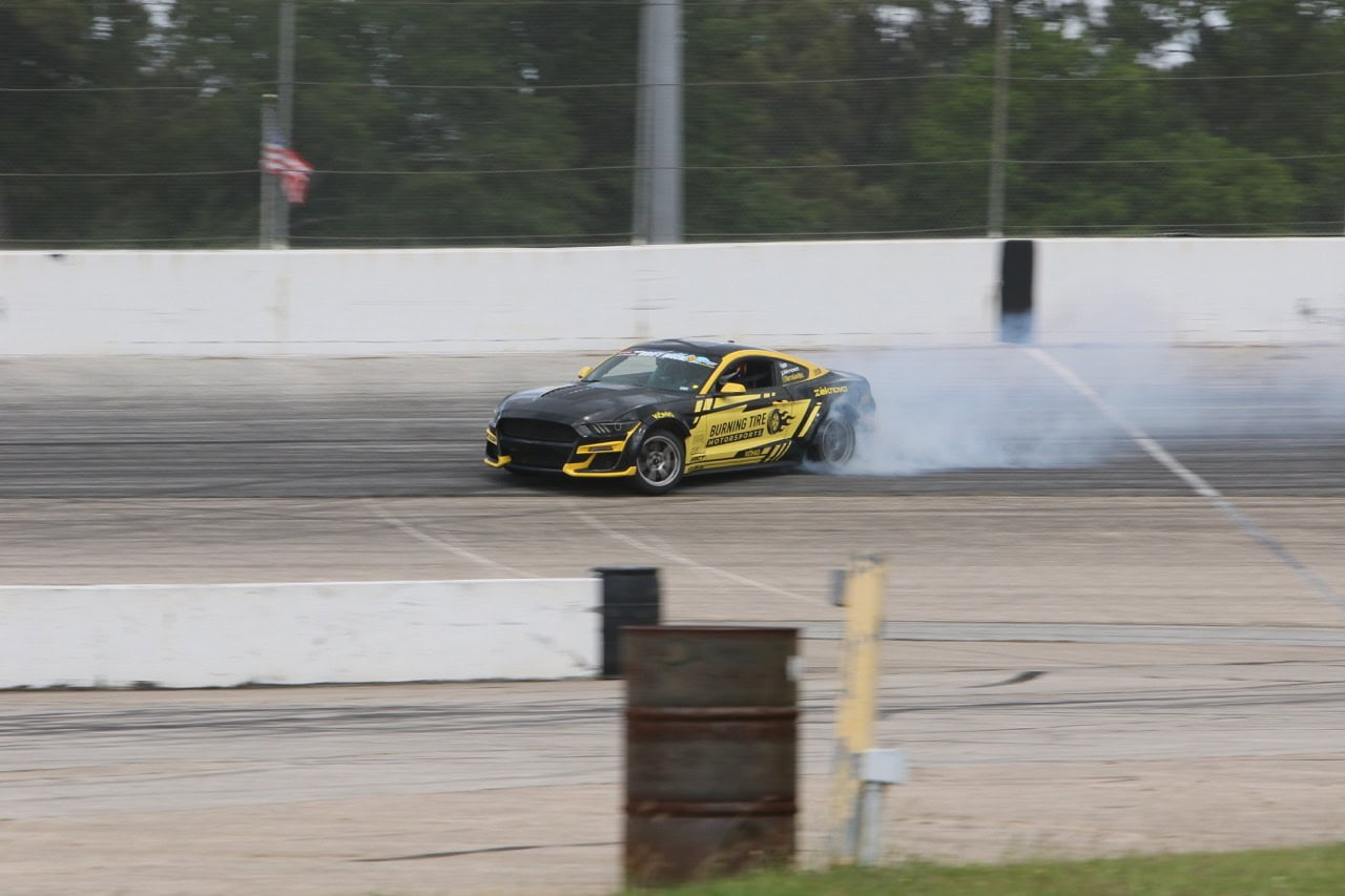 High-performance Mustang drifting on race track during Mustang Week event.