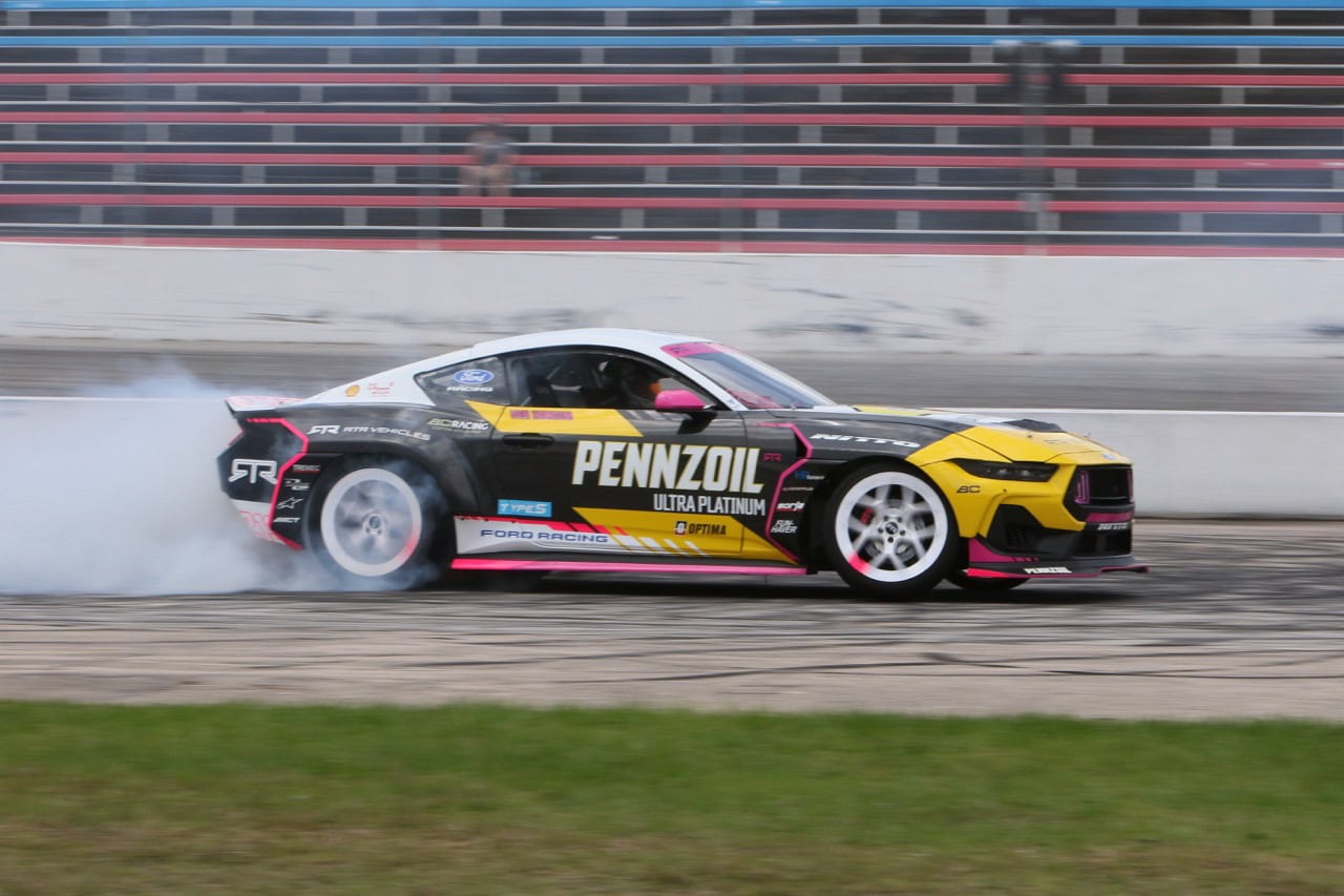 Mustang race car drifting on track during Mustang Week event.