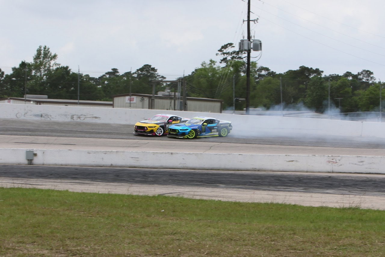 Two Ford Mustangs drifting on a race track during Mustang Week event.