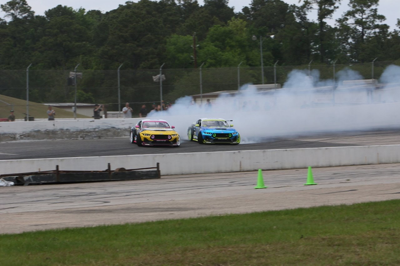 Two race cars drifting on track during Mustang Week event in Texas 2026.