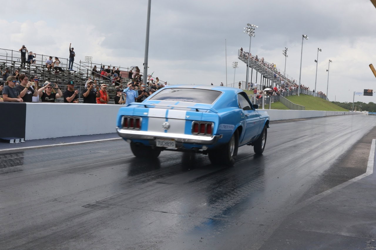 Classic blue Ford Mustang racing on the drag strip at Mustang Week event.
