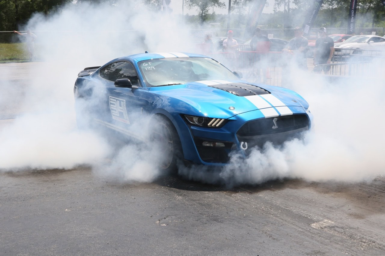 Blue Ford Mustang performing burnout at Mustang Week event.