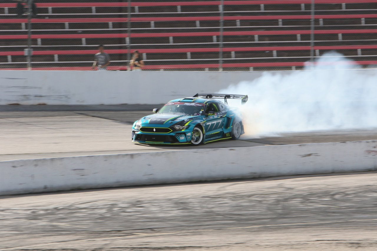 High-performance Mustang racing car drifting at Mustang Week event.