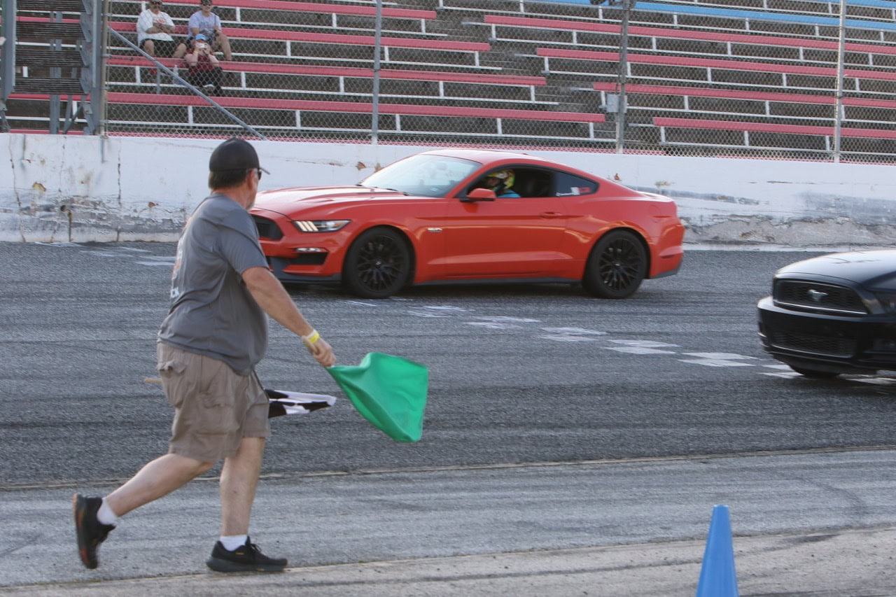 Red Ford Mustang participating in a drag race at Mustang Week event.
