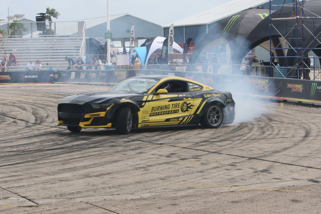 Black and yellow Mustang drifting at Mustang Week event.