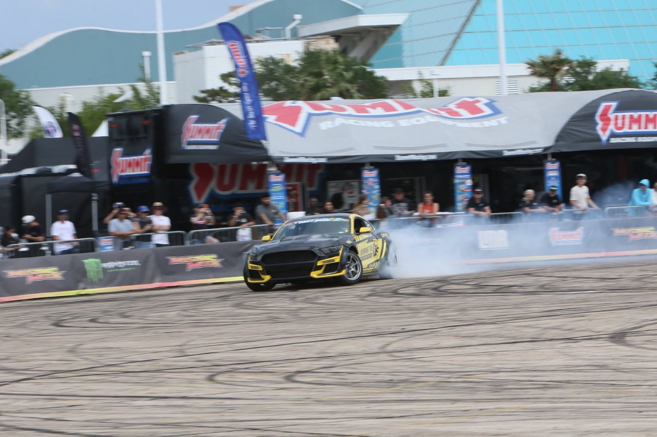 Black and yellow Mustang performing a drift at Mustang Week event.