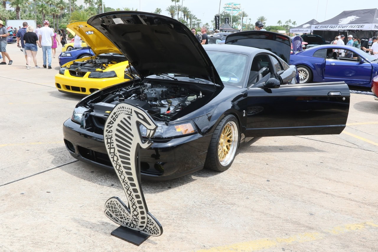Black Ford Mustang with open hood at car show.