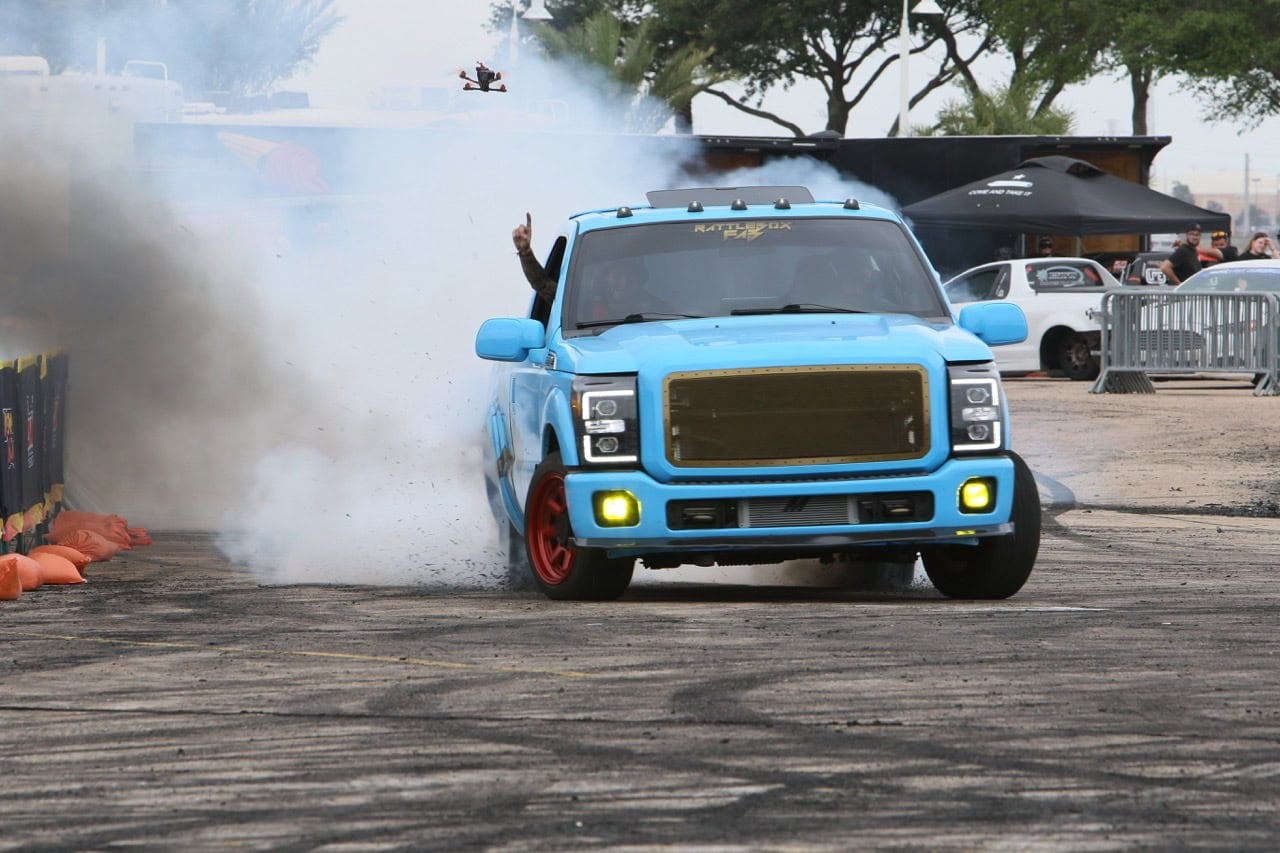 Custom blue Ford truck performing burnout at Mustang Week event.