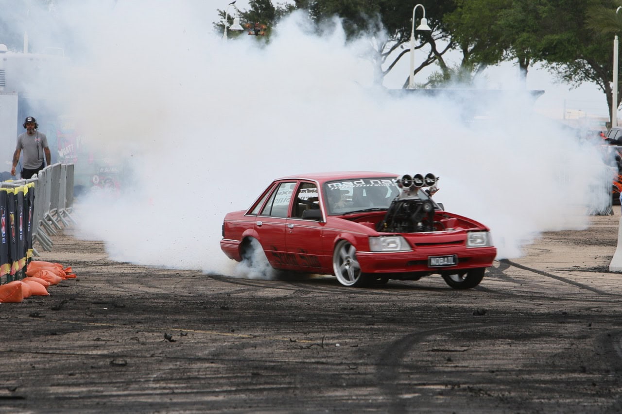 Red Ford Mustang performing burnout at Mustang Week event.