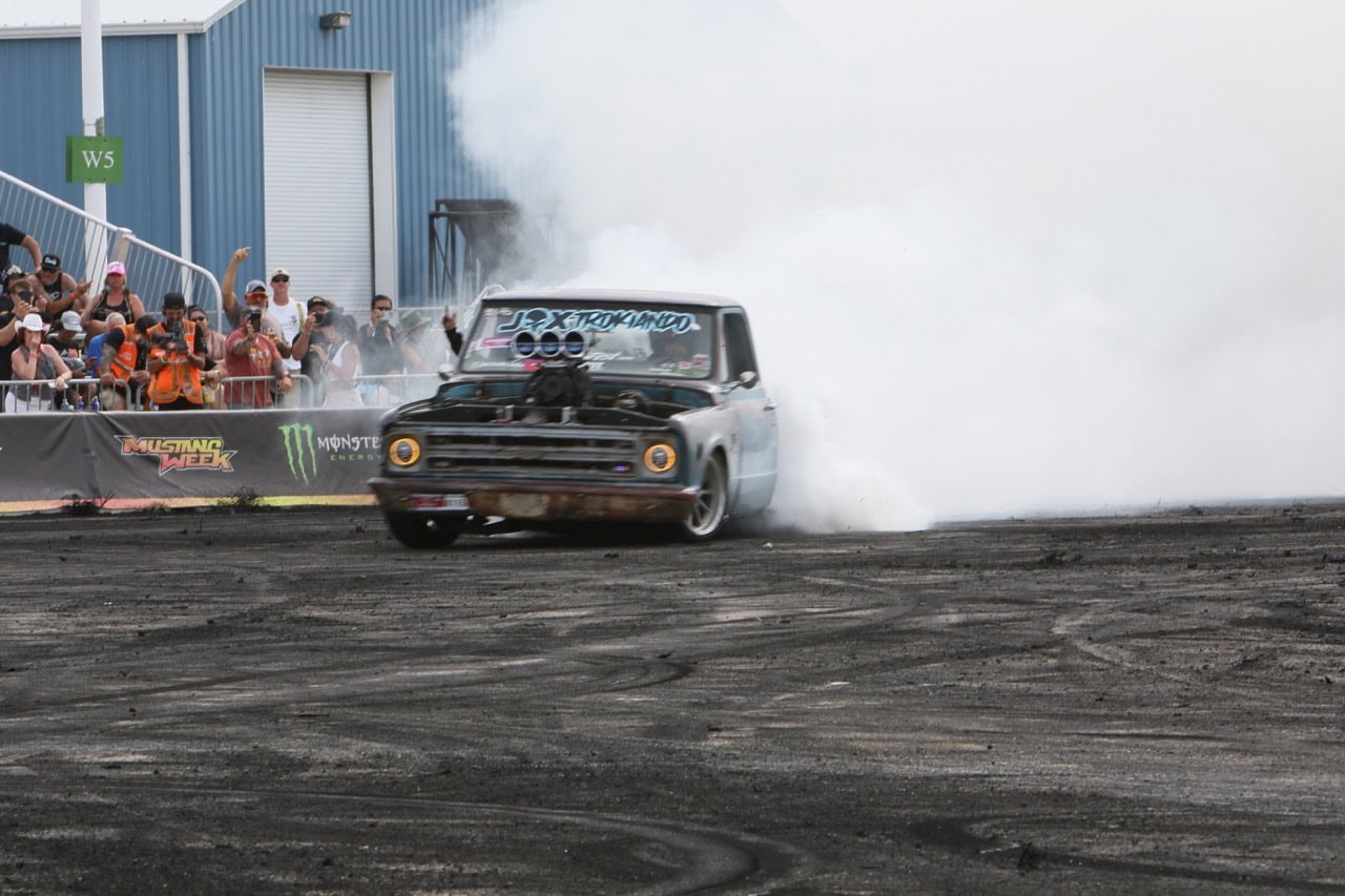 Mustang Week drag racing event with a classic car performing burnouts.