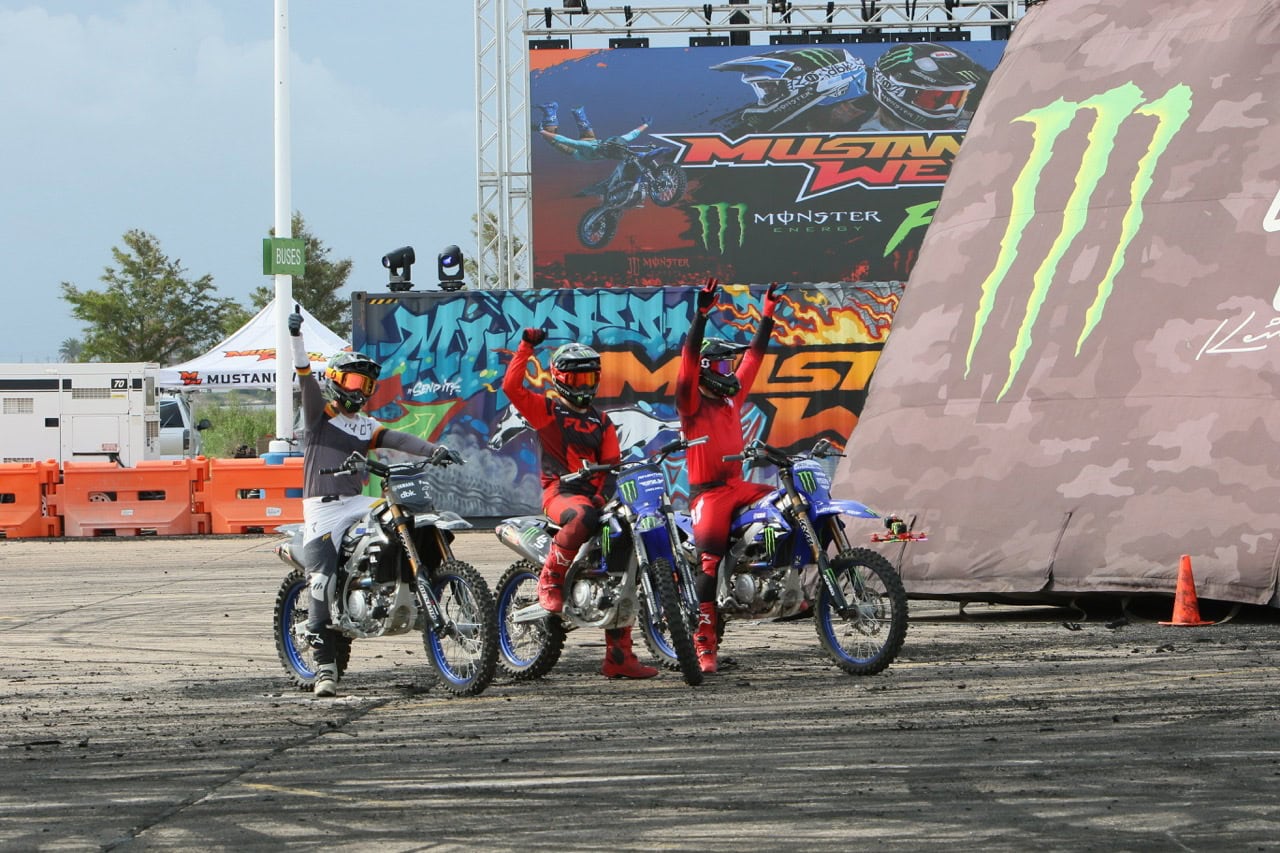Motocross riders celebrating at Mustang Week event with bikes and racing gear.