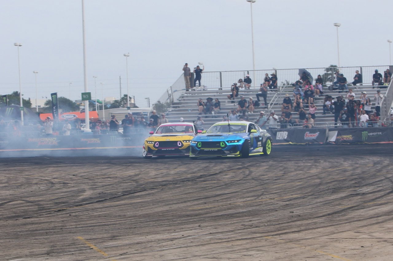 Two Ford Mustangs drifting on the race track during Mustang Week event.