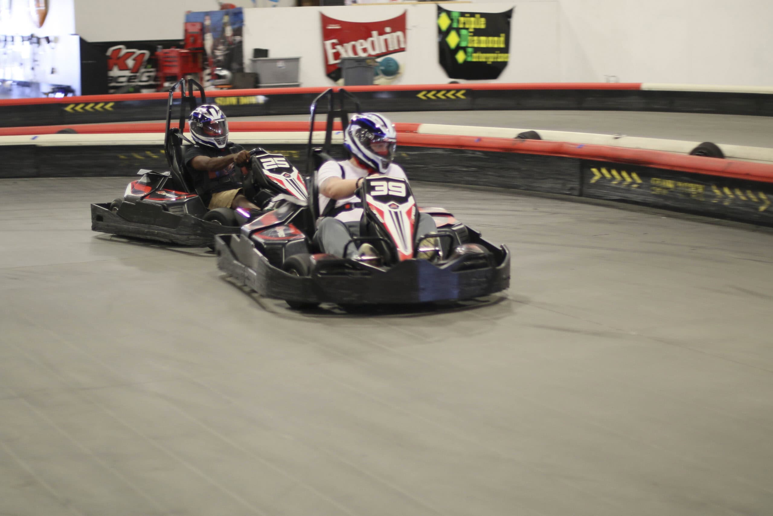 Two racers in go-karts competing on an indoor track at Mustang Week event.