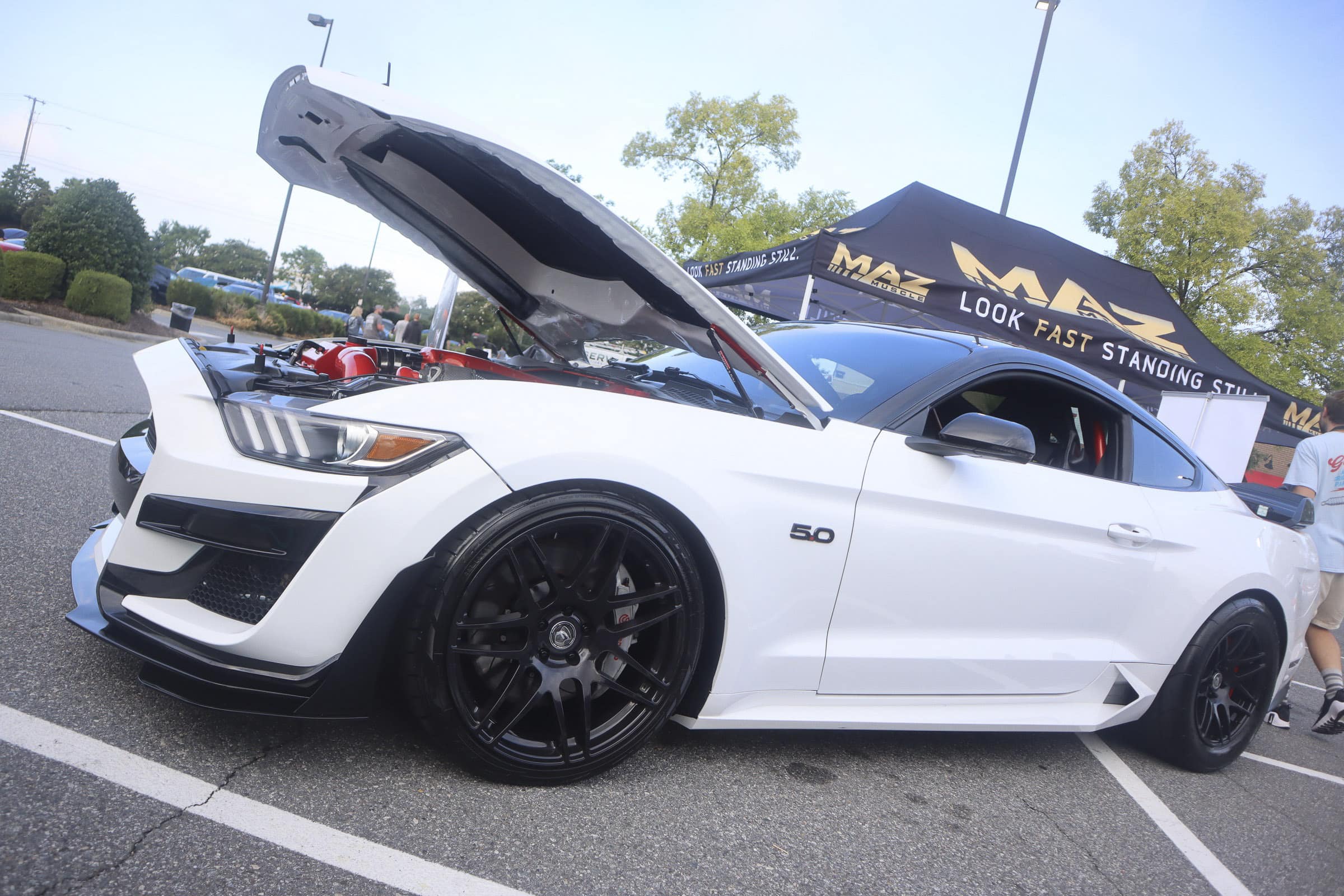 White Ford Mustang with open hood at Mustang Week event.