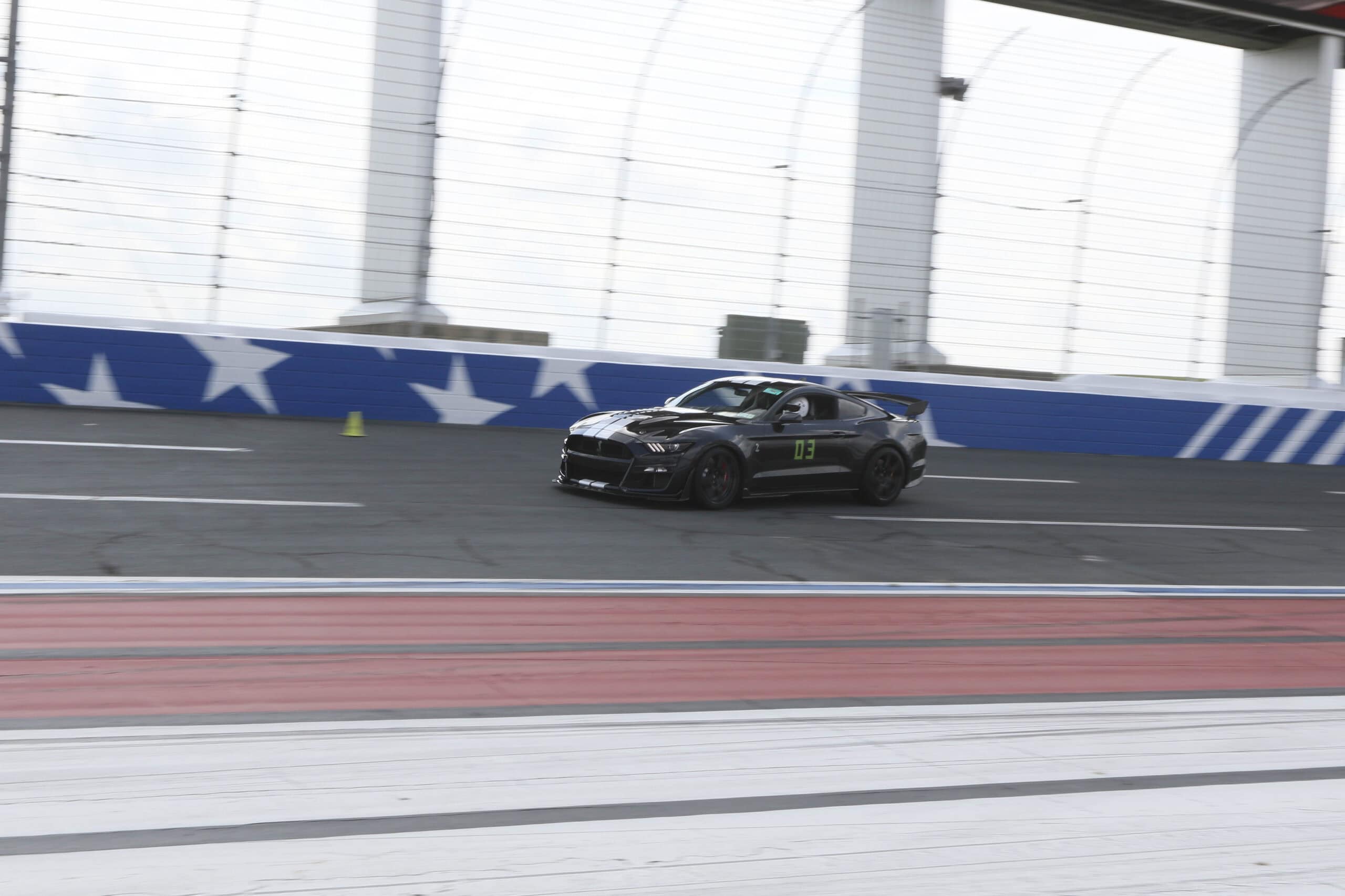 Black Mustang race car on indoor racing track at Mustang Week.